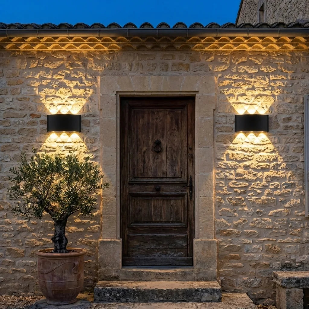 Fekete LED fali lámpák egy kőház bejárati ajtaja mellett alkonyatkor