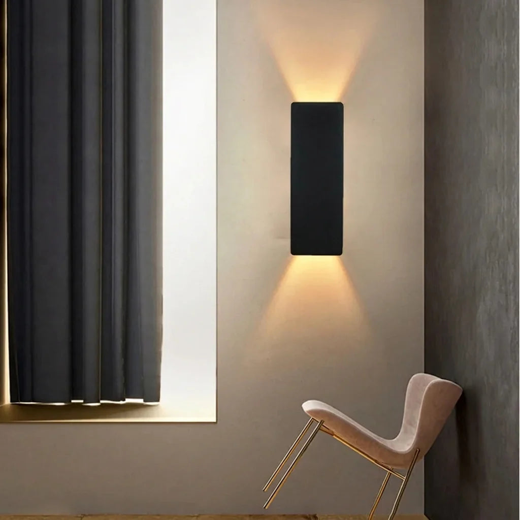 Fekete LED lap fali lámpa egy púderrózsaszín fotel fölött